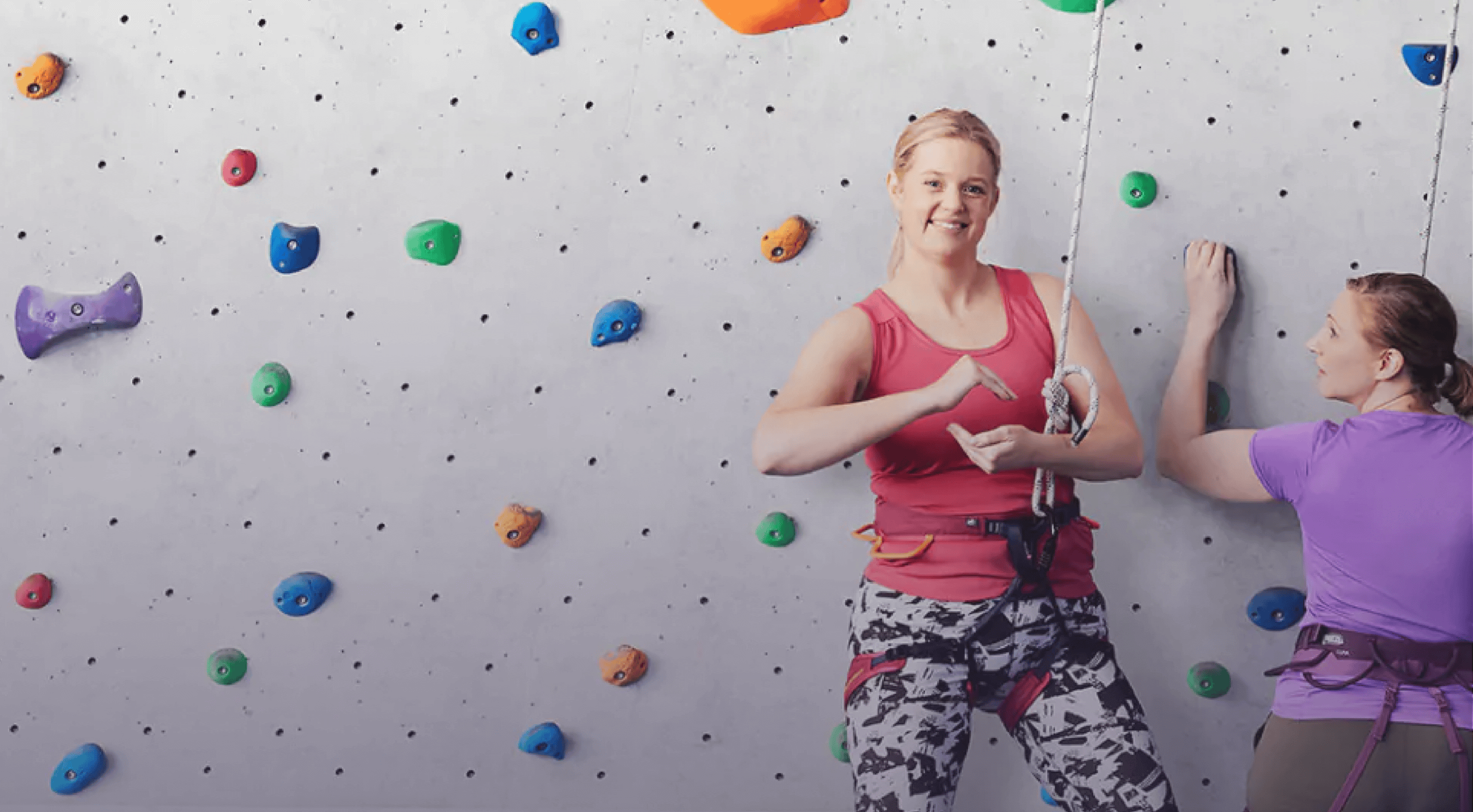 Two women rock climbing up a wall